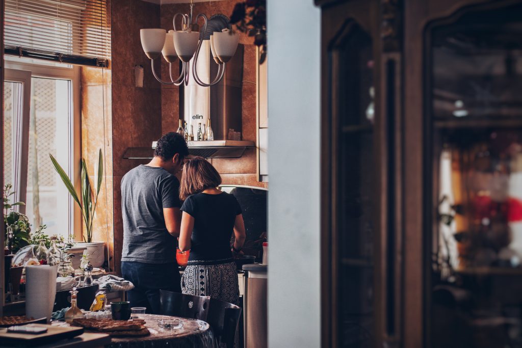 A couple cooking food together indicating committed intimate relationship