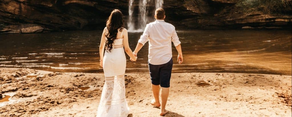 A couple walking near a water fall holding their hands